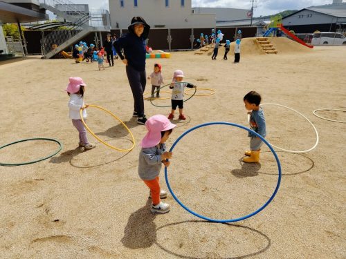 5月7日:フラフープを腰で回そうとする友達の真似っこをしています。先生は回せないので格好だけです。