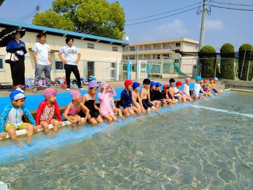 7月10日：豊小学校のプールに行きました。先生の話をよく聞いて、プールでの約束をしています。